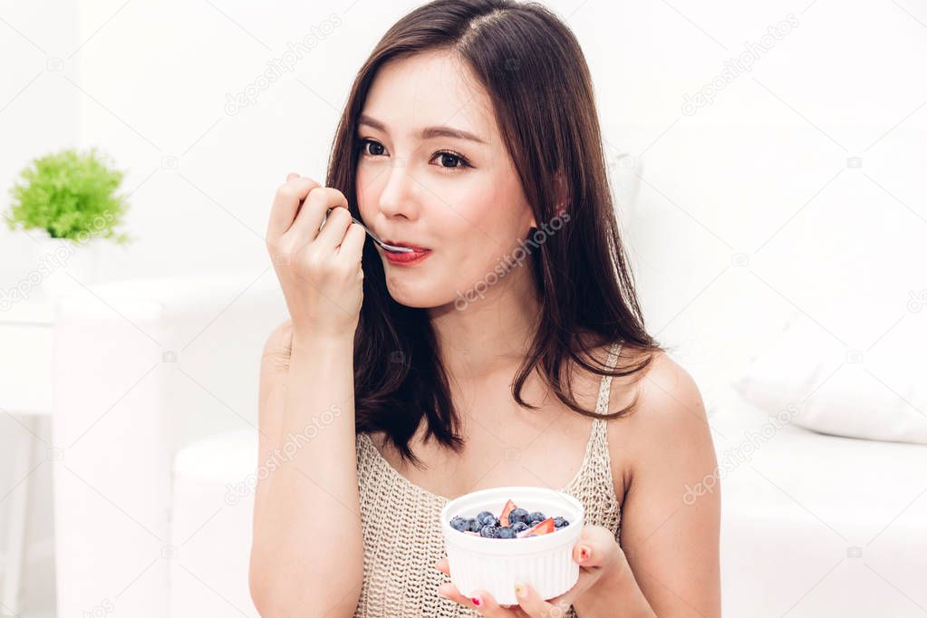 Woman holding yogurt and mixed berries blueberries with strawberries while relaxing at home.dieting concept.healthy lifestyle
