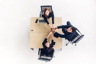Üstten görünüm başarılı grup iş insan yığını ve ellerini birlikte ofis ahşap masa üzerine koyarak. Dostluk ekip çalışması kavramı