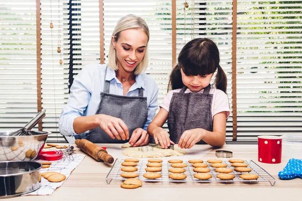 Mother and daugthter having fun cooking togather and learning to make a cake while baking in kitchen at home