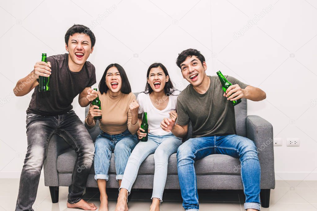 Group of friends drinking beer together and watching soccer game on sofa at home.Friendship and party concept