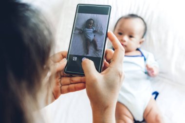 Anne ile bebek beyaz bir yatak odasında smartphone kullanın. Aşk aile kavramının