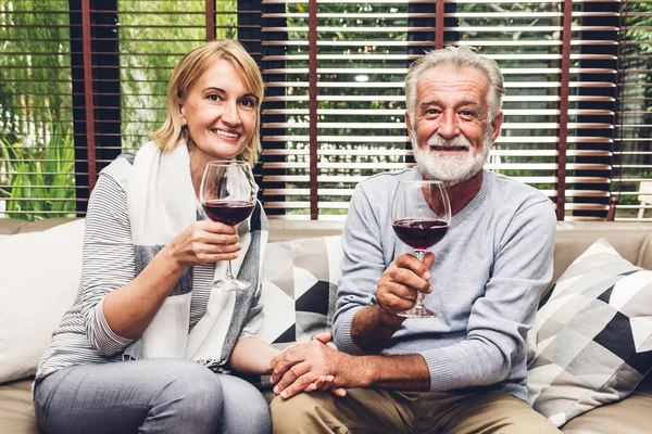 Senior couple relax talking and drinking wine glasses together on sofa in living room at home.Retirement couple concept