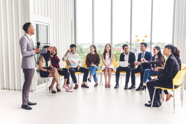 Salon veya seminer odasındaki danışmanlık konferansı seminerinde bir grup insanın önünde duran iş adamı. Sunum ve koçluk konsepti