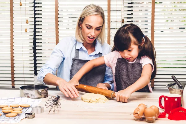 Mother and daugthter having fun cooking togather and learning to make a cake while baking in kitchen at home