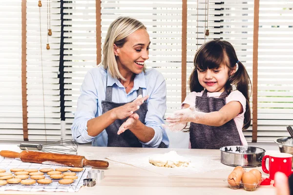 Mother and daugthter having fun cooking togather and learning to make a cake while baking in kitchen at home