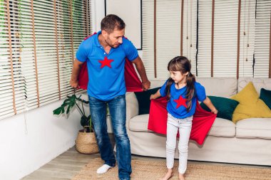 Baba küçük kızı eğleniyor ve süper kahramanlar birlikte oynayan süper kahraman kostümü ile. Gün kavramı, Aile ve baba sevgisi