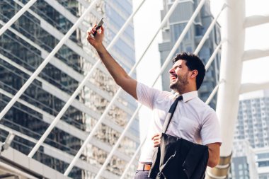 Ayakta ve smartphone açık havada teknoloji cihazlar konsepti ile çalışan modern şehir background.man kullanarak siyah elbiseli yakışıklı işadamı portresi