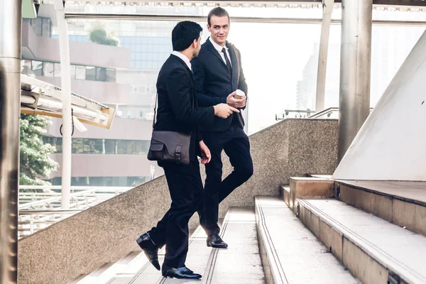 Two smiling businessman coworkers in black suit talking and walk — Stock Photo, Image