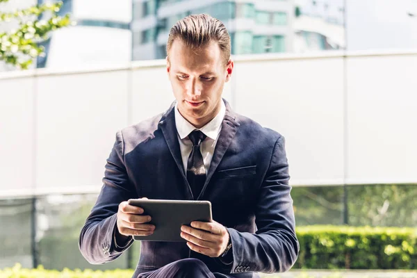 Portrait of handsome businessman in black suit using tablet outd — Stock Photo, Image