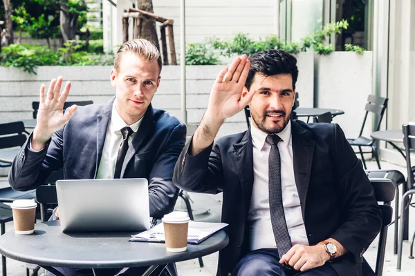 Handsome businessman in black elegant suit smiling at camera wav — Stock Photo, Image