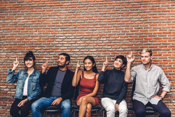 Gruppe von Geschäftsleuten, während sie auf einem Stuhl sitzen und auf Leere zeigen — Stockfoto