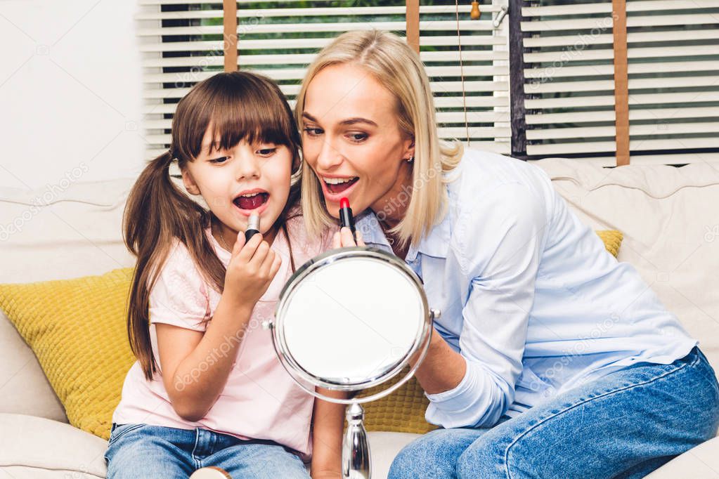 Mother with little daughter having fun and doing makeup cosmetic