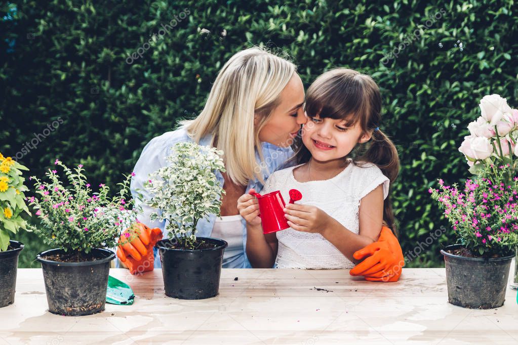 Mother with little daughter having fun and planting flowers in p