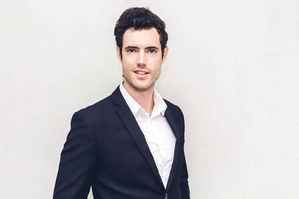 Portrait of handsome smiling businessman in black suit standing — Stock Photo, Image