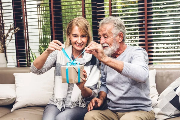 Happy smiling elder senior man giving anniversary gift box surpr