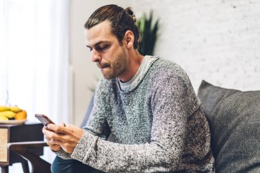 Rahatlayan ve akıllı telefon kullanan genç adam. Sosyal uygulamaları kontrol eden adam.