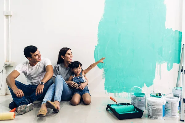 Família feliz usando um rolo de tinta e paredes de pintura em sua ne — Fotografia de Stock