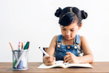 Okul çocuk küçük kız öğrenme ve kalem ile deftere yazma