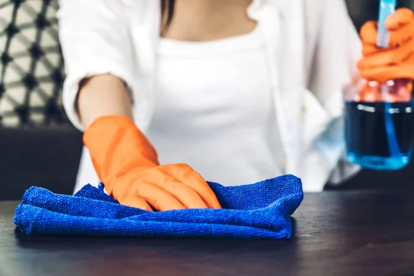 Giovane donna con guanti protettivi usando uno spray e uno straccio mentre cerchio — Foto Stock