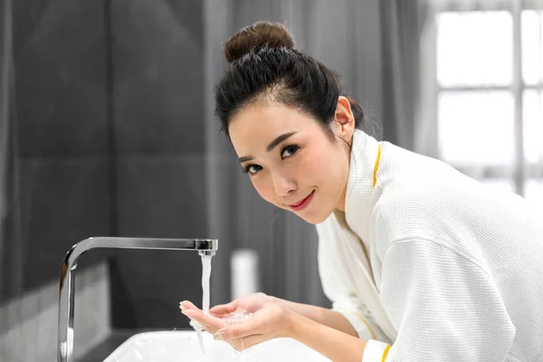 Szép fiatal ázsiai nő mosás tiszta arc vízzel és SM — Stock Fotó