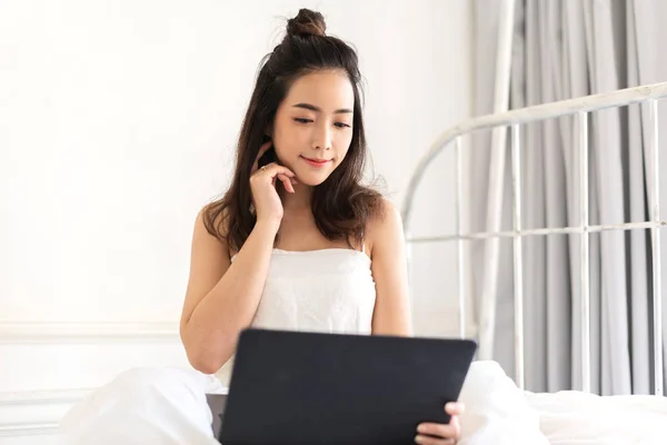 Mujer joven que se relaja con el ordenador portátil en el bedroom.woman —  Fotos de Stock