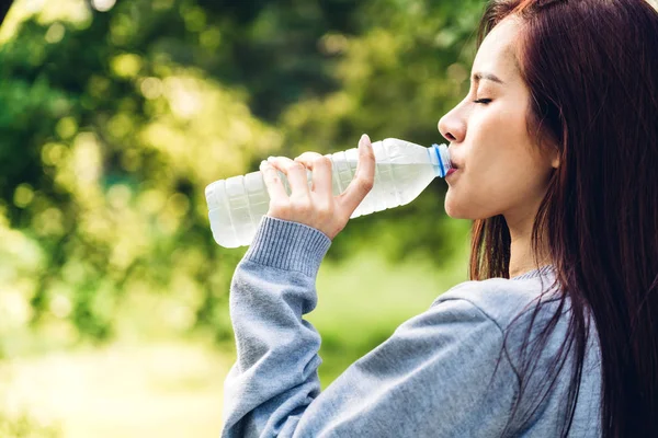 Beautiful asia woman drinking water from a bottle while relaxing