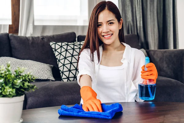 Jovem mulher em luvas de proteção usando um spray e pano enquanto cle — Fotografia de Stock