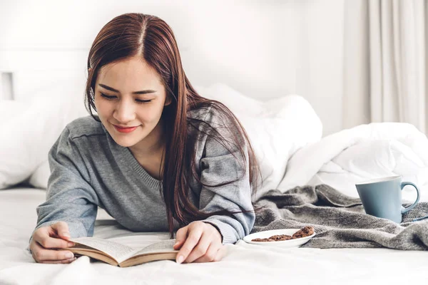 Joven mujer relajante lectura libro y beber taza de café caliente —  Fotos de Stock