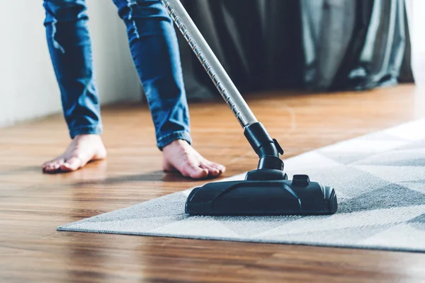 Junge Frau in Schutzhandschuhen putzt Haus mit Staubsauger — Stockfoto