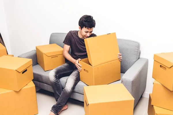 Щасливий молодий чоловік розпаковує коробку і переїжджає в свій новий будинок. — стокове фото