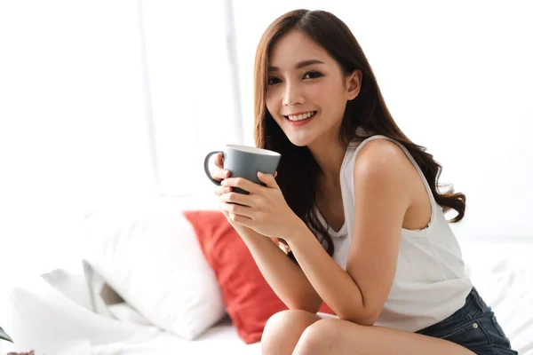 Woman drinking coffee in bedroom in the morning — Stock Photo, Image