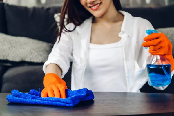 Giovane donna con guanti protettivi usando uno spray e uno straccio mentre cerchio — Foto Stock