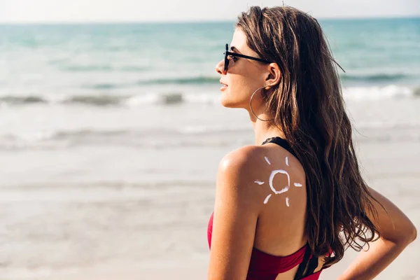 Kvinna klädd i två bit bikini ansöker solkräm med sol dras — Stockfoto