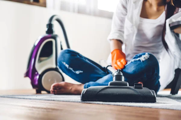 Junge Frau in Schutzhandschuhen putzt Haus mit Staubsauger — Stockfoto