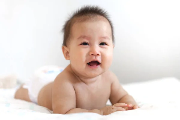 Portret van een blije glimlach baby ontspannen op het bed — Stockfoto