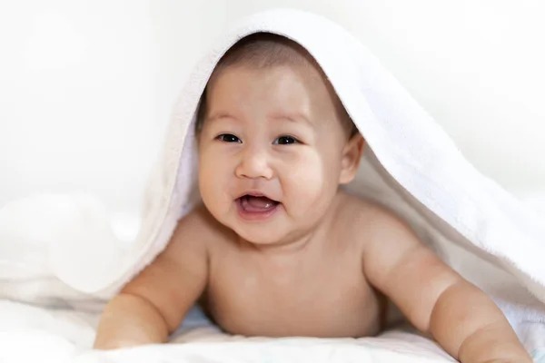 Retrato de la sonrisa feliz bebé relajándose bajo la toalla después del baño en — Foto de Stock