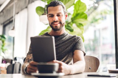 Yakışıklı sakallı hipster adam tablet bilgisayar whil kullanarak rahatlatıcı