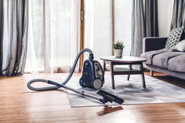 Evdeki oturma odasında elektrikli süpürge var.