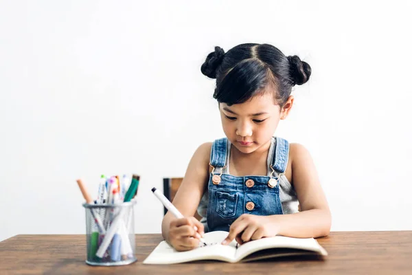 Okul çocuk küçük kız öğrenme ve kalem ile deftere yazma — Stok fotoğraf
