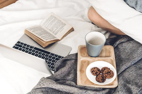 Laptop en kopje koffie met boek op het bed — Stockfoto