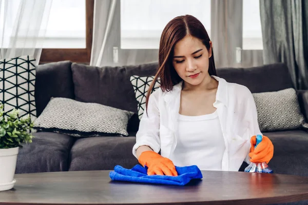 Junge Frau in Schutzhandschuhen mit Spray und Lappen — Stockfoto