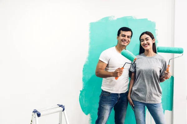 Lyckligt par med en färg rulle och målning väggar i sin Ne — Stockfoto