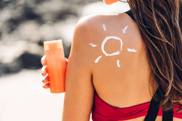 Mulher vestindo biquíni de duas peças aplicando protetor solar com sol desenhado — Fotografia de Stock