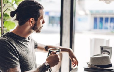 Yakışıklı sakallı hipster adam rahatlatıcı tutarak ve cof ile içki