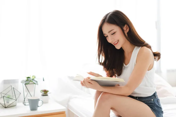 Mujer joven lectura relajante libro en la cama en casa —  Fotos de Stock