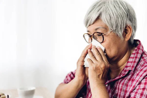 Sick senior woman blowing her nose with paper tissue and sneezin — Stock Photo, Image