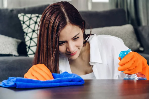 Giovane donna con guanti protettivi usando uno spray e uno straccio mentre cerchio — Foto Stock