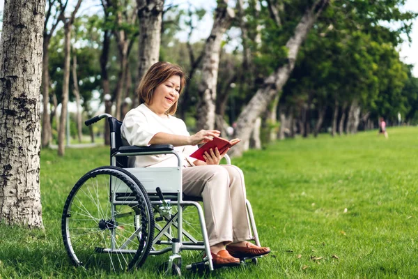 Senior volwassen ouderen Azië vrouwen zitten op een rolstoel en het lezen van Bo — Stockfoto