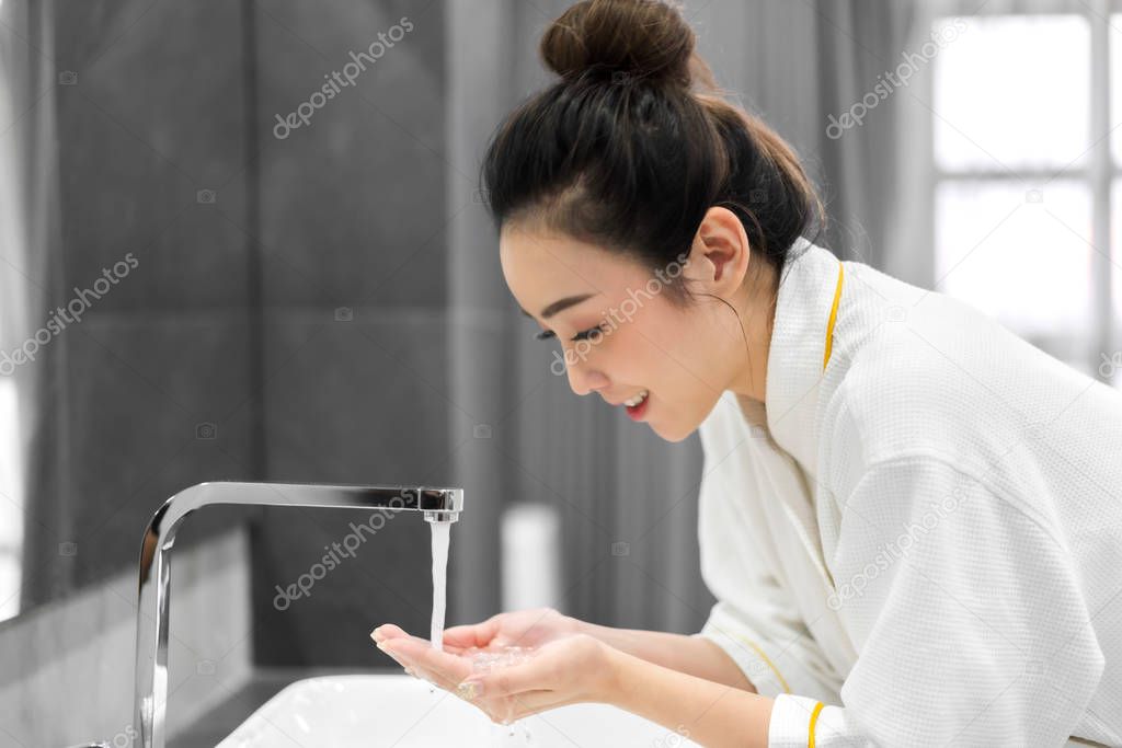 Beautiful young asian woman washing clean face with water and sm