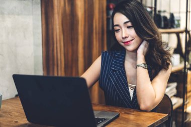 İş kadını oturma ve dizüstü bilgisayar ve içki ile çalışıyor